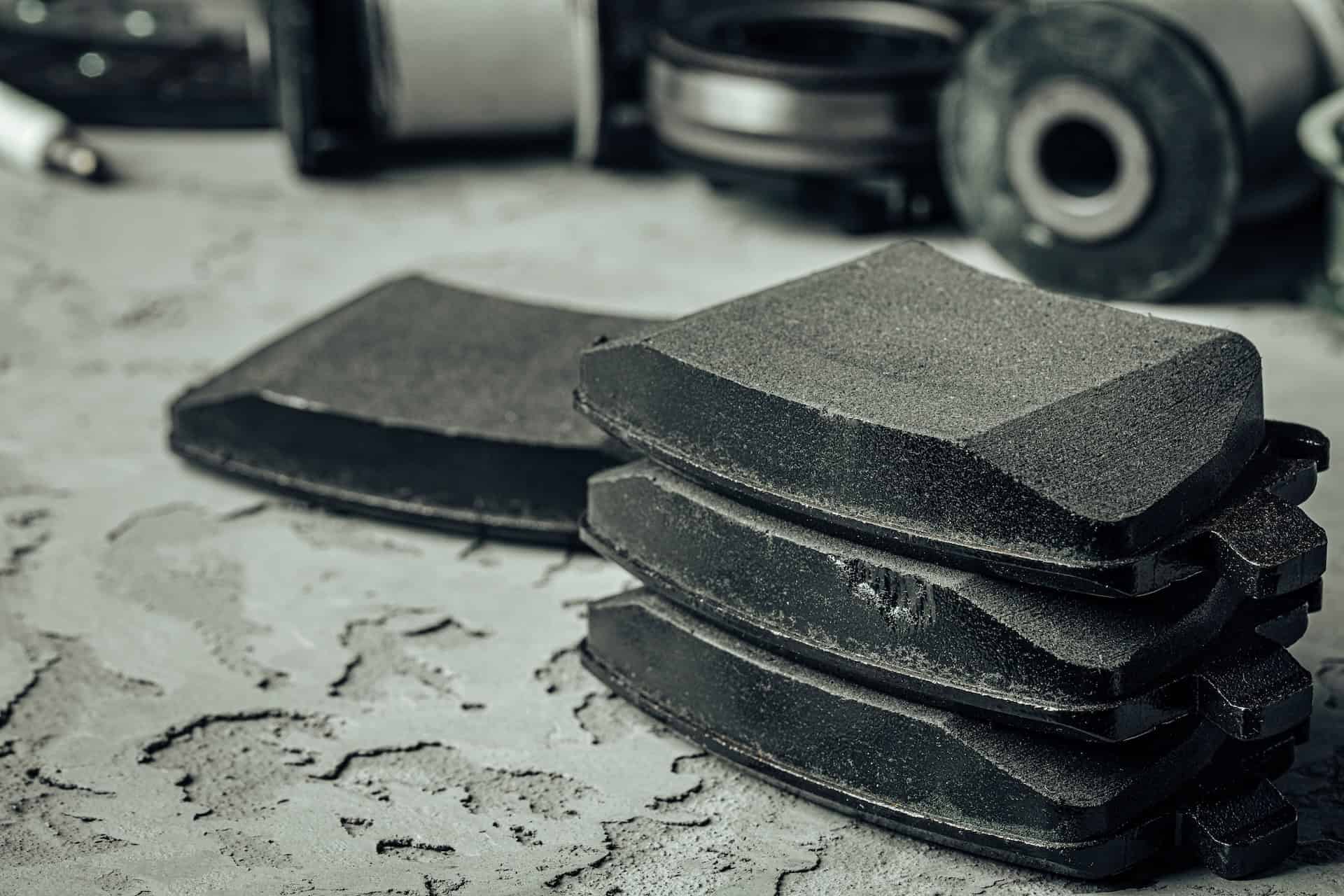 Stack of car brake pads in a workshop for a guide explaining how long do brake pads last and when they need replacing